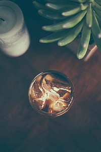 drinking glass beside white pillar candle and succulent plant thumbnail