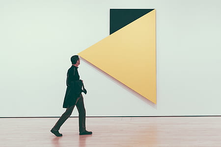 man carrying black textile walking past yellow wall decor thumbnail