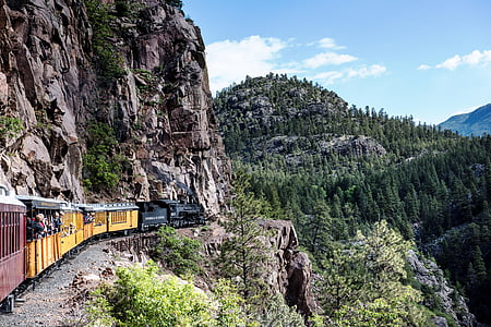 locomotive train passing on hills under skies thumbnail