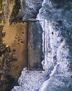 black rock formation near body of water during daytime thumbnail