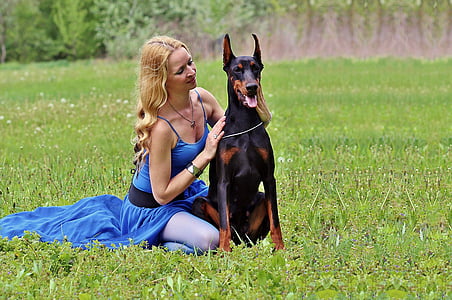 woman holding black and tan Doberman pinscher during daytime thumbnail