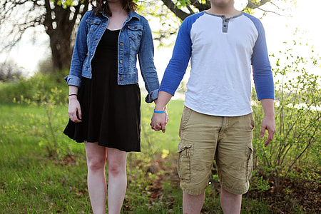 man and woman holding hands while standing on green grass field thumbnail