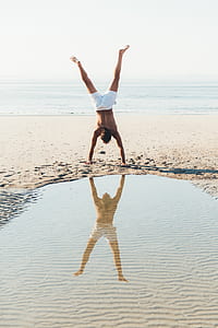 man wearing white shorts near body of water during daytime thumbnail