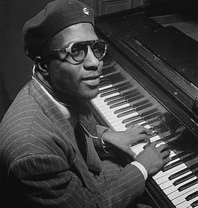 greyscale photo of man playing piano inside room thumbnail