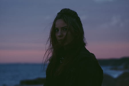 woman standing near body of water during golden hour thumbnail