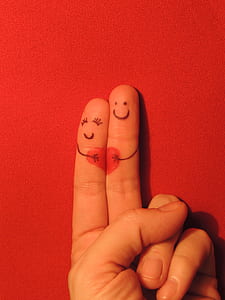 person's finger with smiling face holding heart thumbnail