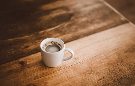 white ceramic cup with coffee on brown wooden surface thumbnail