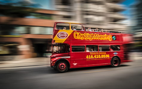 red double-decker bus passing by building thumbnail