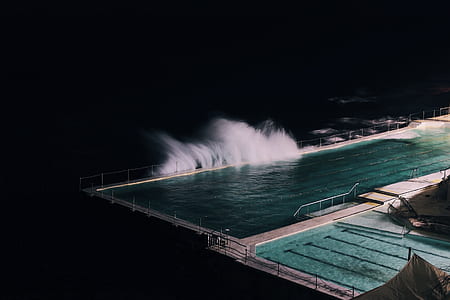 sea wave banging on seawall with Olympic size swimming pool thumbnail