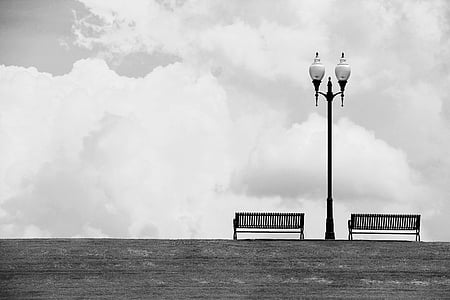 grayscale photo of lamp post near two benches thumbnail