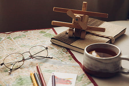 brown propeller plane miniature near white ceramic mug and black eyeglasses thumbnail