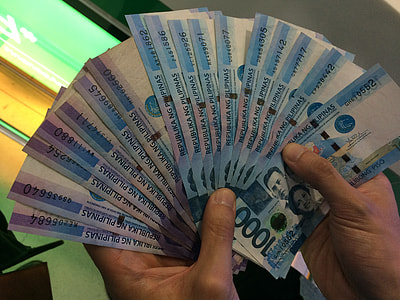 person holding bundle of 1000 Philippine peso banknotes thumbnail