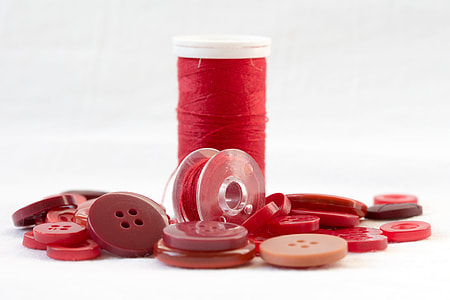 red thread spool surrounded with buttons thumbnail