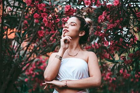 woman wearing white tube top near red petaled flowers thumbnail