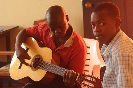 boy playing guitar beside boy wearing polo thumbnail