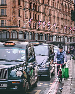 man in blue and gray hoodie jacket cycling beside London taxi thumbnail