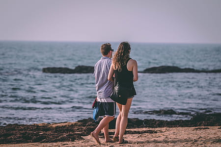 man and woman walking at the shore during daytime thumbnail