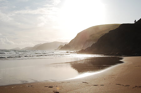 seashore near mountain during daytime thumbnail