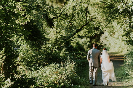 groom and bride walking on garden during daytime thumbnail