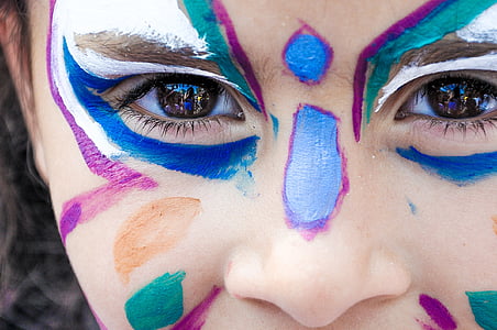 close view of person's face with blue, teal, and white face paint thumbnail