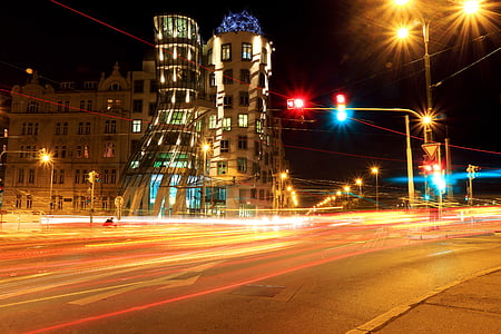 time lapse photography of vehicle passing on road in front of concrete building at night time thumbnail