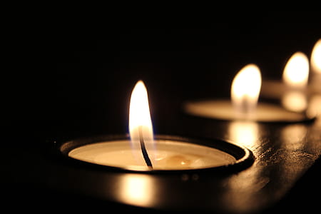 lighted candles on brown wooden candle rack close-up photography thumbnail