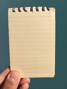 human hand holding beige ruled book thumbnail