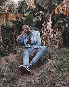 man sitting near banana tree making hand gesture thumbnail