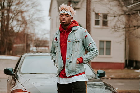 man wear distressed denim jacket standing near car thumbnail