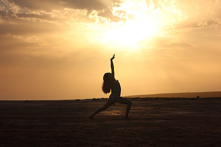 silhouette photo of woman doing yoga in open field during sunrise thumbnail