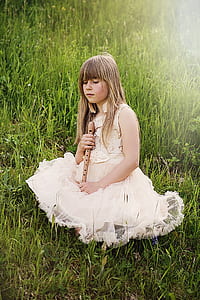 girl holding brown flute on grass field thumbnail