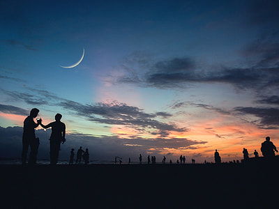 silhouette of people under crescent moon during golden hour thumbnail