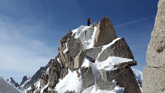 person standing on black monolith covered with snow thumbnail