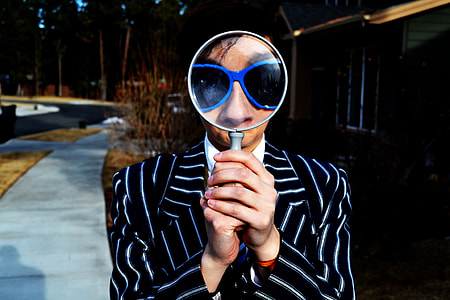 man holding magnifying glass near green wooden house thumbnail
