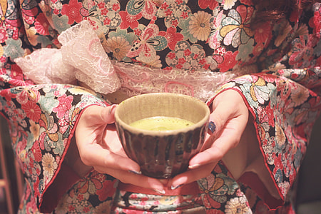 woman wearing red, white and teal floral dress holding white ceramic bowl thumbnail