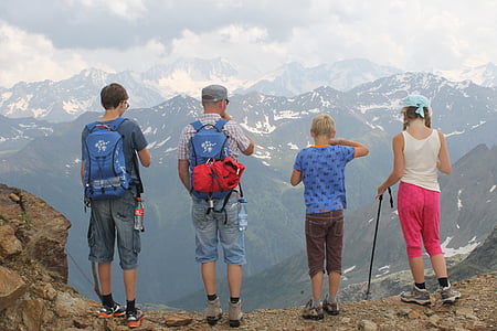 four person standing near cliff facing mountains thumbnail