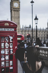 woman taking a photo of red telephone booth thumbnail