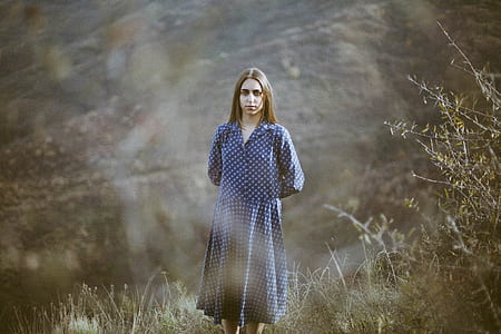 woman wearing blue and white long-sleeved dress standing on green grass thumbnail