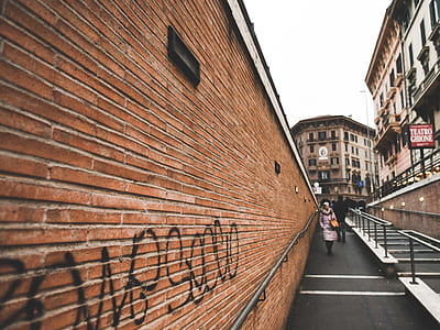 person walking near rail and wall during daytime thumbnail