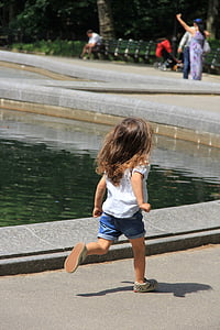 girl wearing white t-shirt runs beside pond at daytime thumbnail