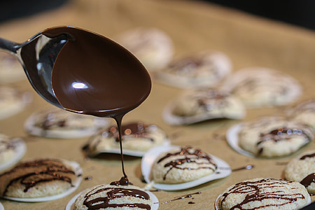 depth of field photography of chocolate dripping through spoon towards cookie thumbnail