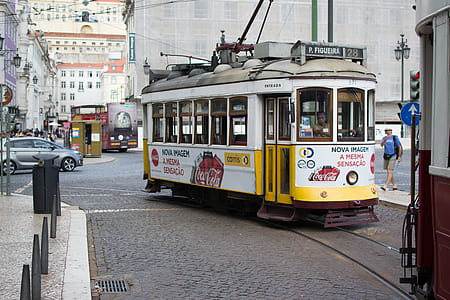 white and yellow train near walking man at daytime thumbnail