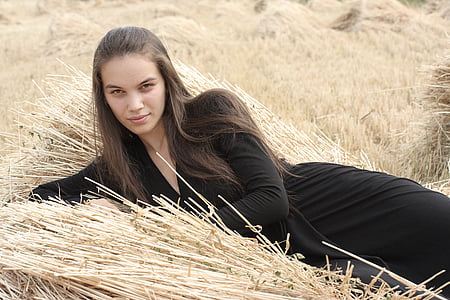 woman wearing black long-sleeved dress lying on hay during daytime thumbnail
