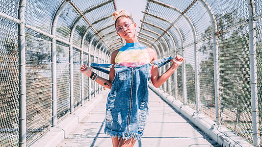 woman in blue dungaree standing between white steel bridge during daytime thumbnail