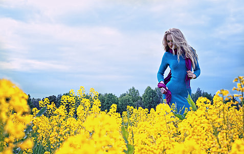 women's wearing blue gown on garden field under blue and white cloudy sky thumbnail
