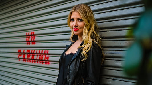selective focus photography of woman leaning against roller shutter thumbnail