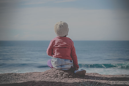 girl wearing red sweater sitting on sand thumbnail