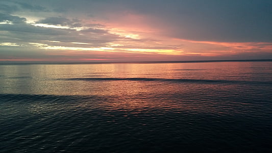 calm sea under cloudy skies during sunset thumbnail