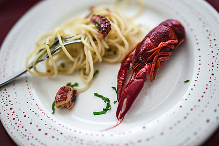 Fancy dinner with seafood pasta, crayfish and red wine by the table decorated with roses thumbnail