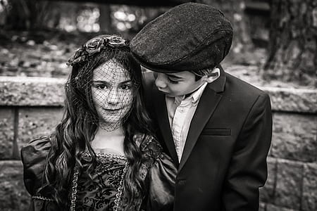 grayscale photography of girl and boy standing beside wall thumbnail
